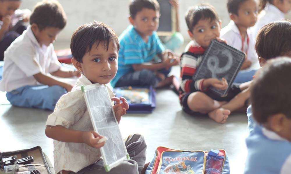 Children holding slate and chalk in school